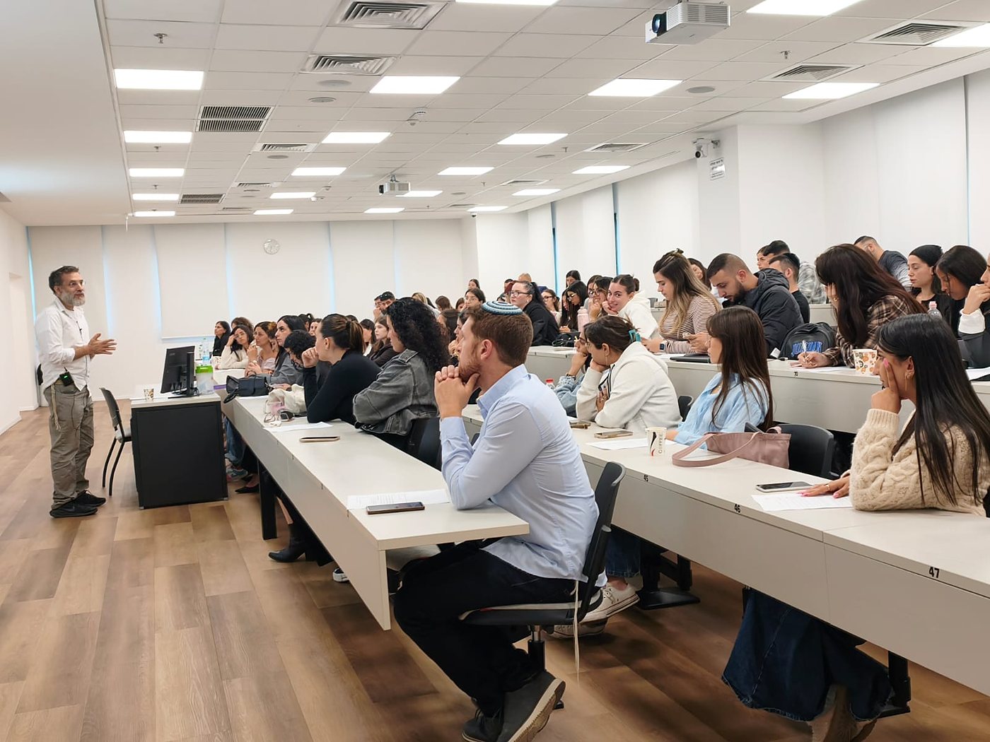A full lecture hall of students listening to a speaker at the Peres Academic Center