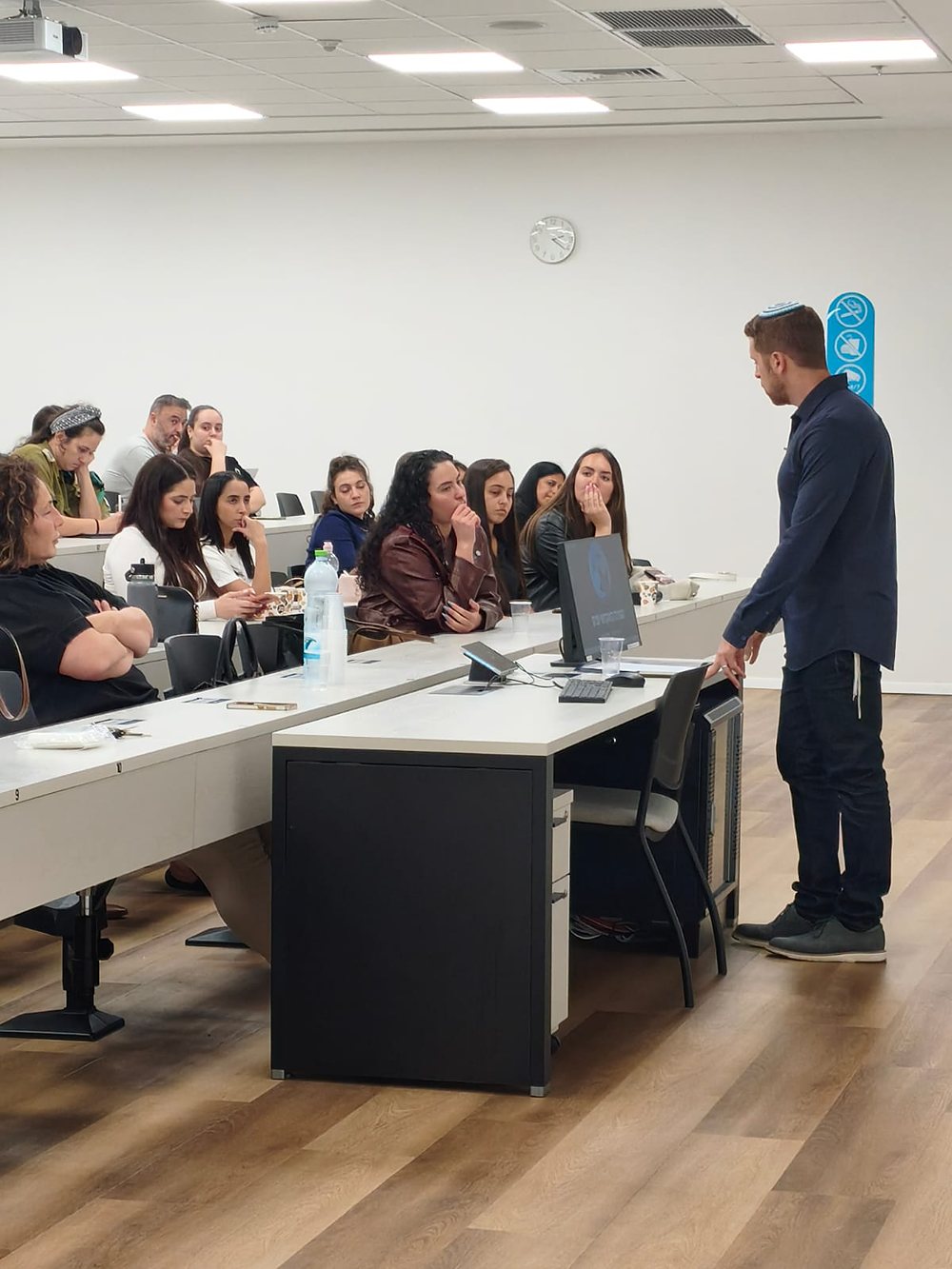 A student standing and speaking to classmates seated around a table