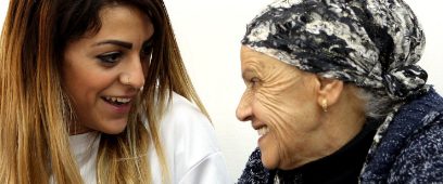 A student volunteer sitting with an older woman